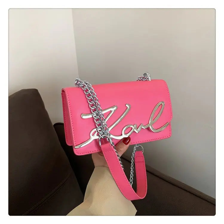 Pink CaRaUaNa Karl Clutch Bag with silver chain strap held by a person against a neutral background