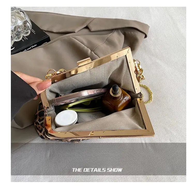 Gold clutch bag with leopard print interior, containing makeup items on a light gray background.