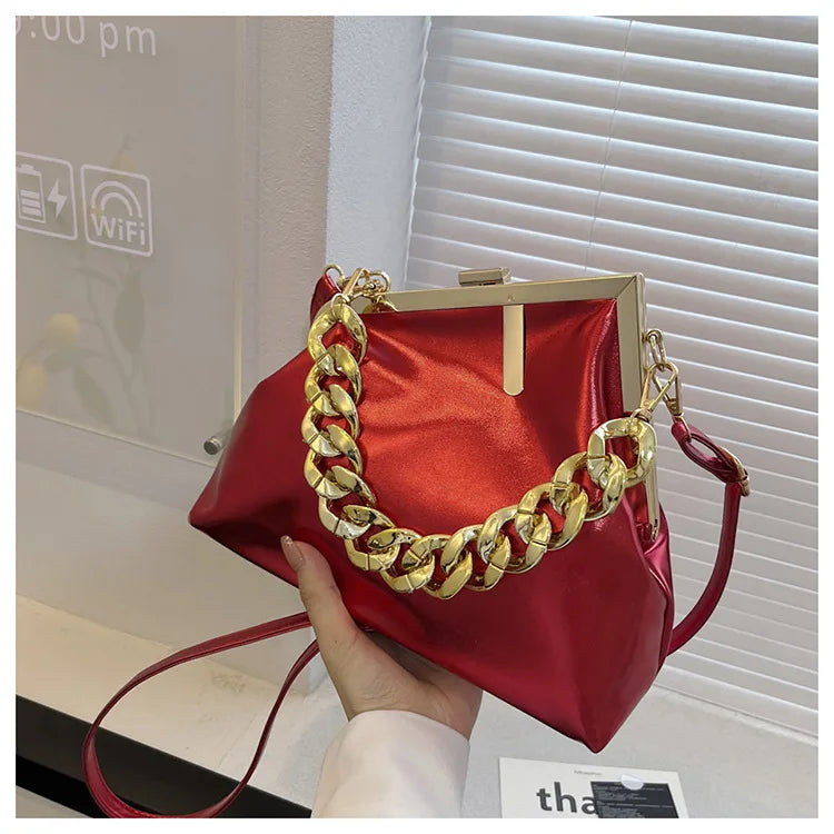 Carauana UNIU Aurora Clutch with gold chain handle held by a hand, indoor setting