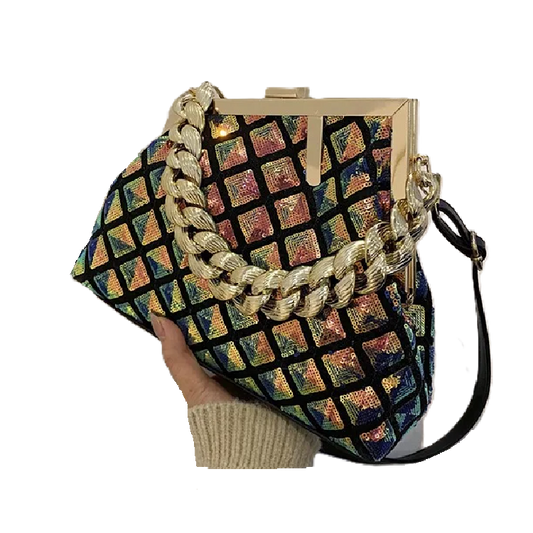 Multicolored patterned handbag with gold chain strap held by a hand on a white background