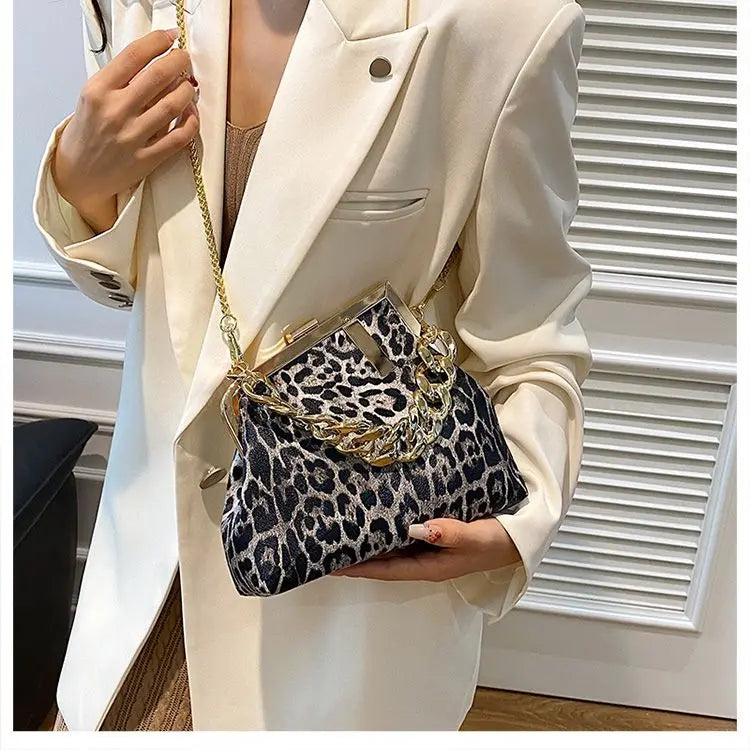 Person holding a Carauana_UNIU_Leopard_Clutch with gold chain detail