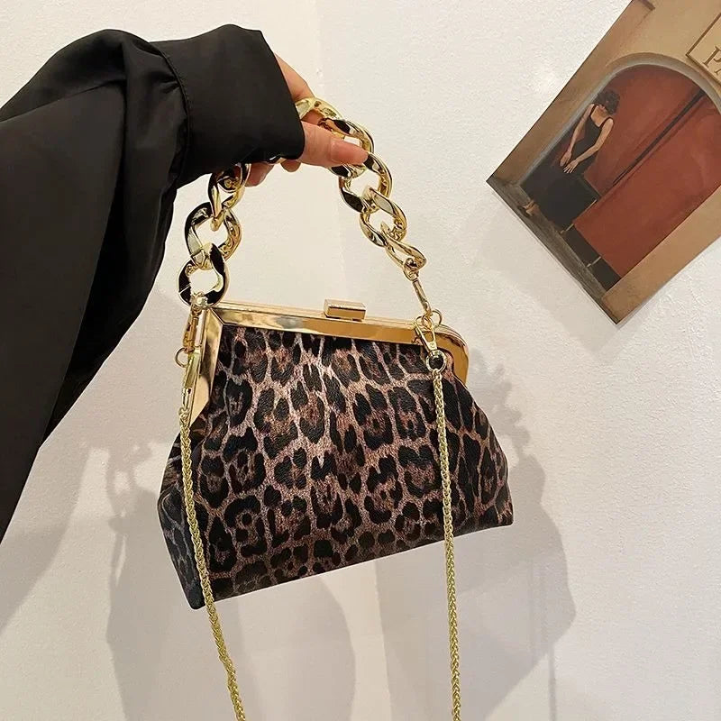 Carauana UNIU Leopard Clutch handbag with gold chain handle held by a person against a neutral background