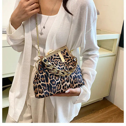 women holding a Carauana_UNIU_Leopard_Clutch with a gold chain strap indoors.