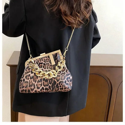 Person holding a Carauana_UNIU_Leopard_Clutch with gold chain detail