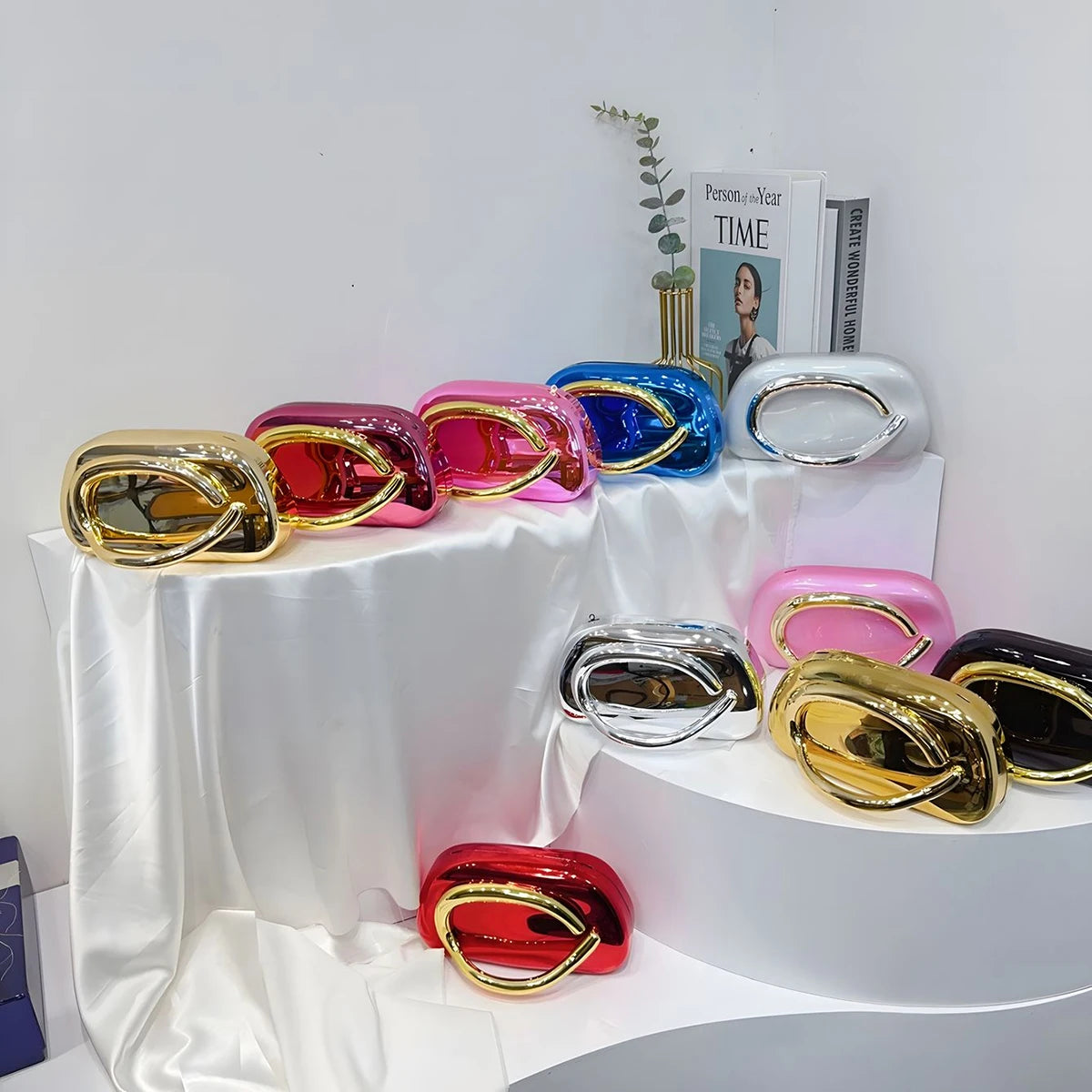 Colorful metallic Carauana Festival Clutch Bag  on a white surface with a magazine in the background.