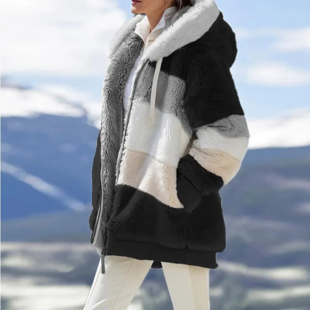 Person wearing a black and gray sherpa jacket with a mountainous background